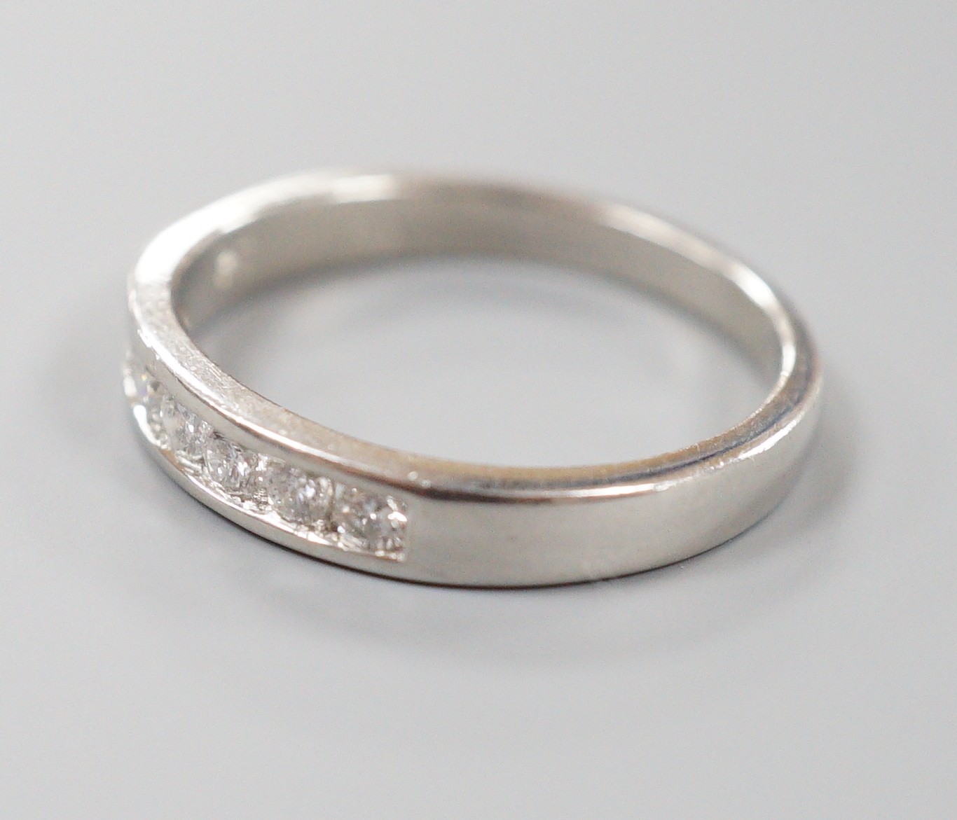 A modern platinum and channel set seven stone half hoop ring, size P, gross weight 5.1 grams